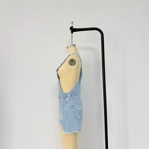 Detail of light blue denim overalls with side metal buttons and distressed ripped texture
