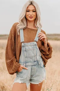 Detail of light blue distressed denim overalls shorts with vintage frayed hems and bib pocket