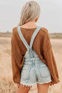 Detail of cross back denim overall shorts with frayed hems and mesh knit top for women