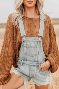 Detail of light blue denim overalls with chest pocket and distressed hem details