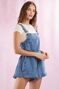 Detail of blue denim romper with chest pocket and waist tie over white knit top