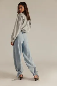 Dettaglio jeans larghi azzurri con coulisse sull'orlo e top grigio a maniche lunghe