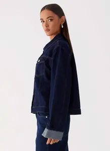 Detailed view of dark blue denim jacket featuring metal buttons and chest flap pockets