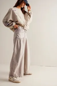 Dettaglio della felpa oversize avena e pantaloni a gamba larga a vita alta sul modello