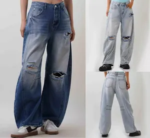 Detail of high-waisted distressed wide-leg jeans with ripped knees and vintage wash