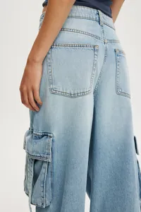 Détail du jean cargo ample avec délavage bleu clair et grandes poches latérales