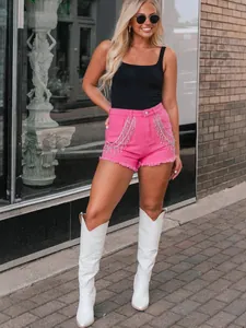 Pink high-waisted denim shorts with rhinestone tassels and raw edges in outdoor street style