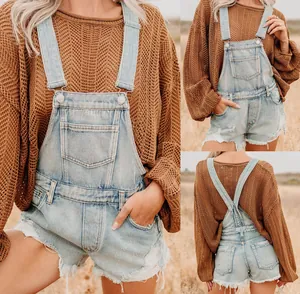 Detail of light blue denim overalls showing frayed hem and hollow-out knit sweater
