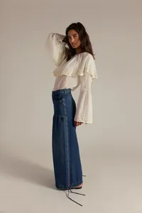 Dettaglio della camicetta bianca a balze abbinata ai jeans blu scuro a gamba larga donna