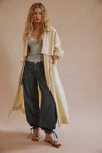 Trench coat lungo beige abbinato a jeans larghi con coulisse per un look casual femminile
