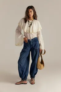 Vista completa di jeans larghi da donna abbinati a camicetta in pizzo e borsa a tracolla