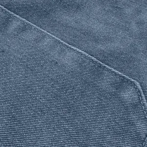 Macro shot of blue-gray denim fabric showing twill texture and precision stitching
