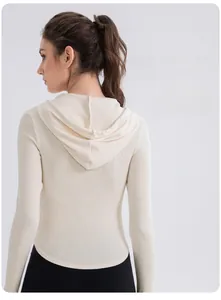 Detail of hooded slim fit yoga top in ribbed fabric showing waist cut and curved hem