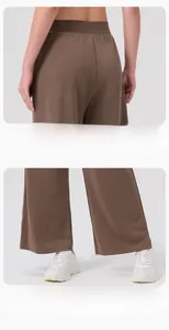 Detail of brown wide-leg yoga pants showing drape texture and high waist fit with sneakers