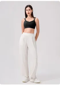 Detail of black cross-back yoga bra with elastic straps and white wide-leg fitness pants