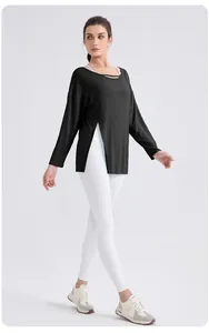 Detail of loose fit black yoga top with deep side slits and white high waist leggings