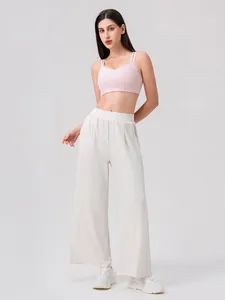 Pale pink yoga bra with thin double straps and off-white wide-leg pants for workout