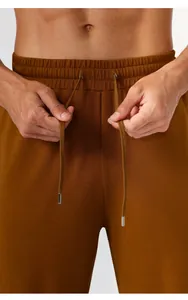 Close-up of men's athletic jogger pants featuring elastic waistband and metal tip drawstring