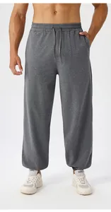 Close-up of men's loose yoga pants featuring drawstring waist and dark gray cotton fabric