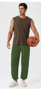 Male athlete wearing olive green joggers and a brown muscle tank holding a basketball