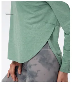 Détail de la fente latérale sur le haut de sport vert sauge à manches longues texturé