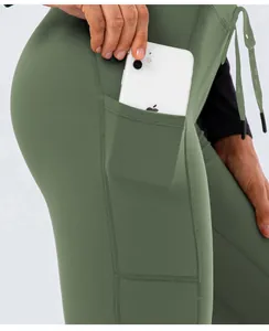 Detail of high-waist olive green yoga pants showing side pocket for phone and drawcord
