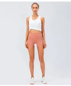 Front view of high waist coral pink yoga shorts with white knot-hem tank top and sneakers