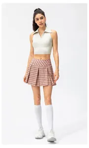 Detail van de crème yoga top met polokraag en roze geruite geplooide tennisrok set