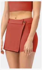 Close-up of clay red yoga skort with decorative button and wrap-style waist detail