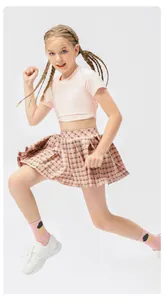 Κορίτσι με ροζ καρό πλισέ φούστα τένις και crop top σε ενεργή στάση τρεξίματος