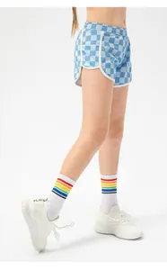Detail of girls' checkered sports shorts with rainbow striped socks and sneakers