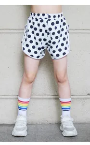 Close-up of kids sports shorts with classic black polka dots and curved hem design