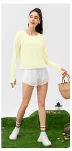 Detail of light yellow long sleeve sun protection top with thumb hole cuffs and white shorts