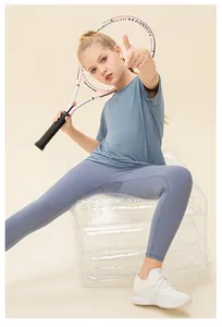 Girl in grey-blue athletic t-shirt and leggings set holding a tennis racket
