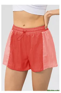 Dettaglio dei pantaloncini sportivi arancioni con elastico in vita e coulisse regolabile