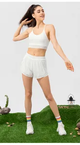 Women's white yoga set with thin strap sports bra and mesh layered shorts in park setting