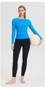 Ensemble haut de yoga bleu roi et legging noir avec un ballon de gym blanc en studio