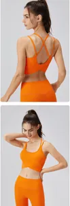 Vue détaillée du soutien-gorge de yoga orange montrant les fines bretelles croisées