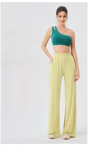 Detail of high-waist light yellow flowy trousers with elastic waistband and draped fabric