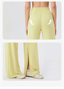 Detail view of high waist elastic band and side slit hem on light yellow flowing trousers