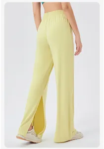 Detail view of high-waisted pale yellow wide-leg yoga pants with side slits and elastic waistband