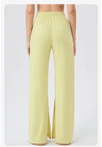 Detail of high-waist yellow wide-leg sports pants with elastic pleated waistband for women