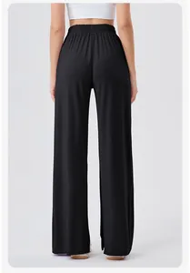 Back view of black high-waisted wide-leg yoga pants showing drape and elastic waistband