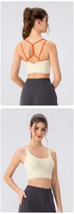 Detail of cross-back orange thin straps on a cream sports bra with gray leggings