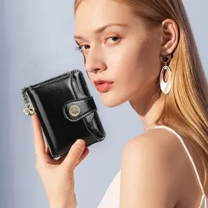 Women's black faux leather short folding wallet with sunflower buckle held by a model