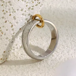 Close-up of dual-tone interlocking chain ring on a minimalist white stone background