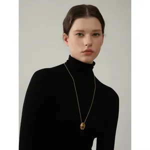 Long collier médaillon ovale minimaliste en or 18 carats sur un col roulé noir