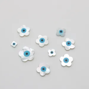 Makroaufnahme von Muschel-Blumenperlen mit Evil Eye Muster für DIY Schmuckdesign