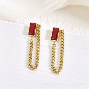 Détails de boucles d'oreilles dorées géométriques avec zircons rouges et glands chaînés