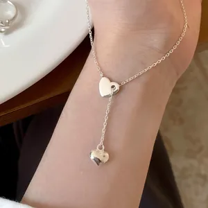 Minimalist silver anklet featuring heart charms worn on ankle with a clean white background